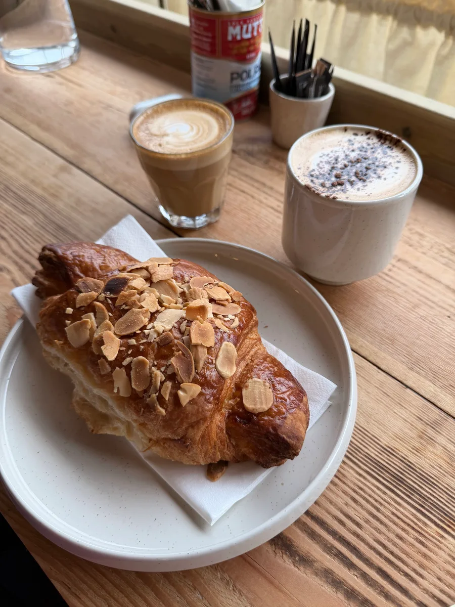 A pastry and coffees on a wooden cafe table
